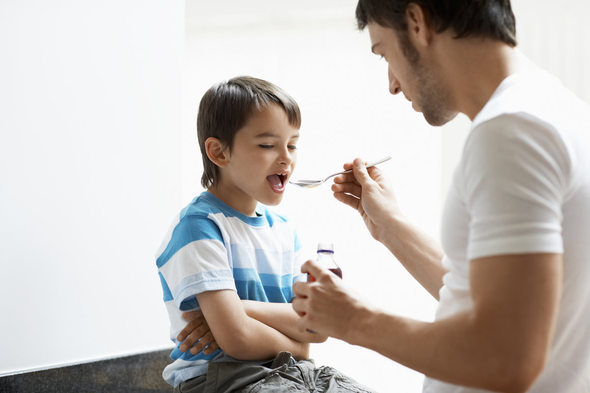Otac daje sinu lijek protiv kašlja.