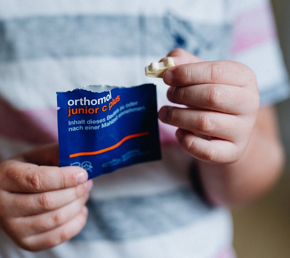 Dijete drži proizvod orthomol junior c plus.