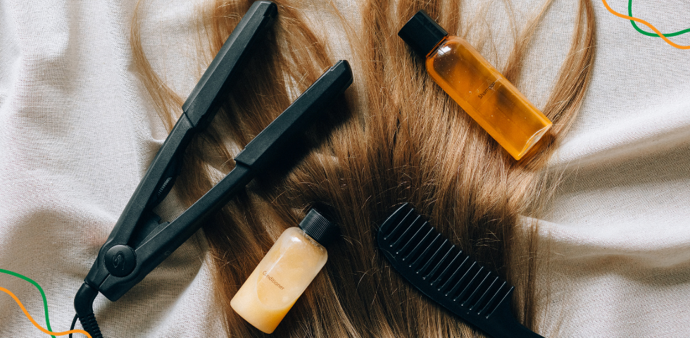 Kosa na kojoj stoji pegla za kosu, češalj i različiti proizvodi.