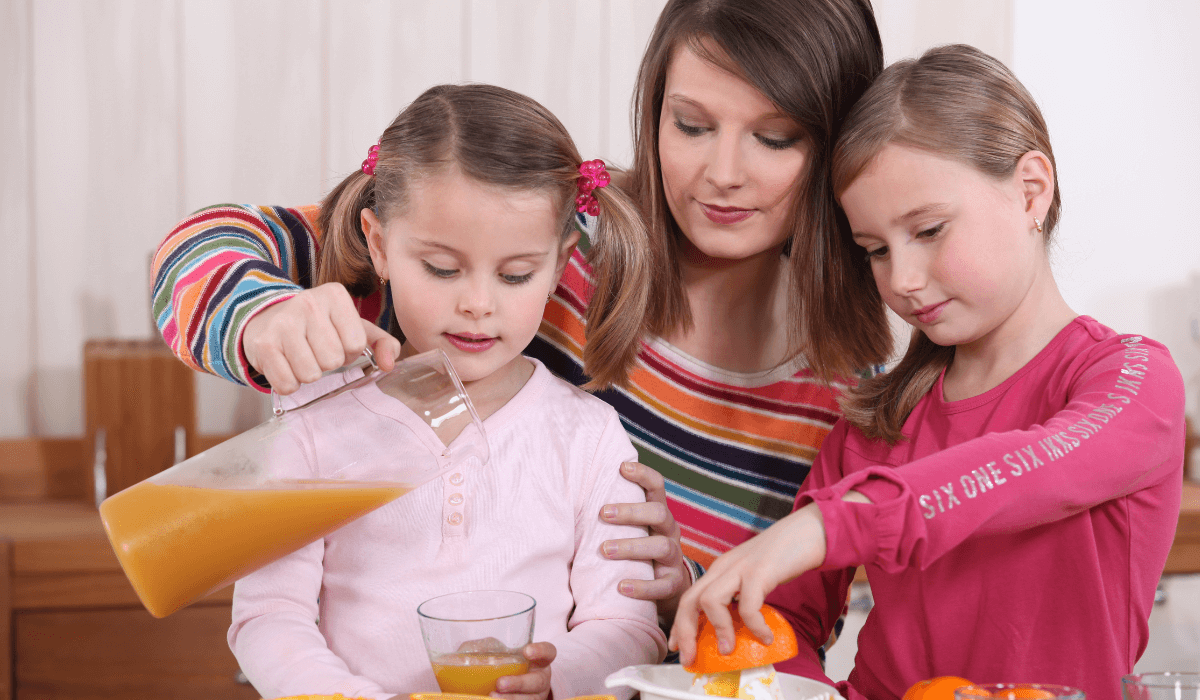 Majka sa dvoje djece koji cijede sok od naranče.