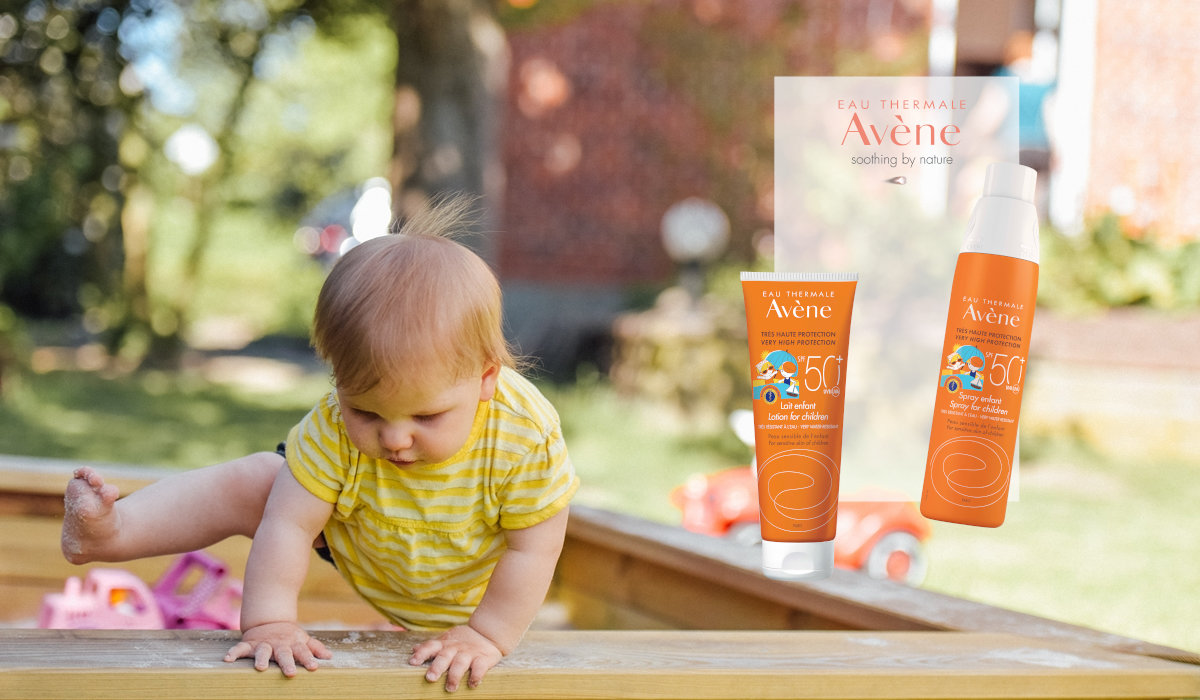 Dijete je u pješčaniku pokraj Avene proizvoda za zaštitu od Sunca.